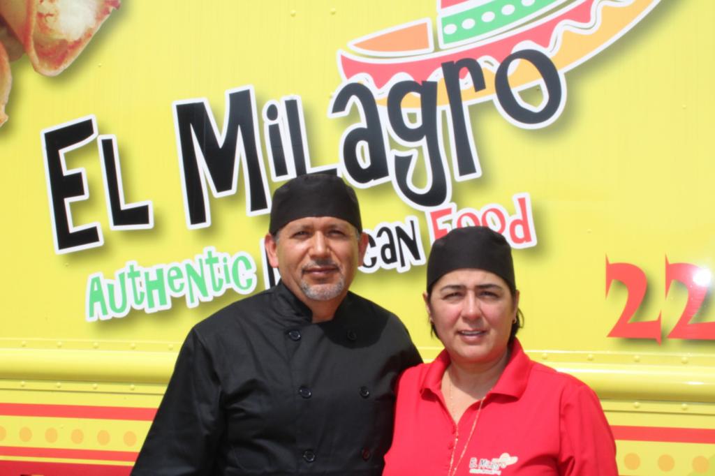 El Milagro owners with their uniform and the food truck behind them,